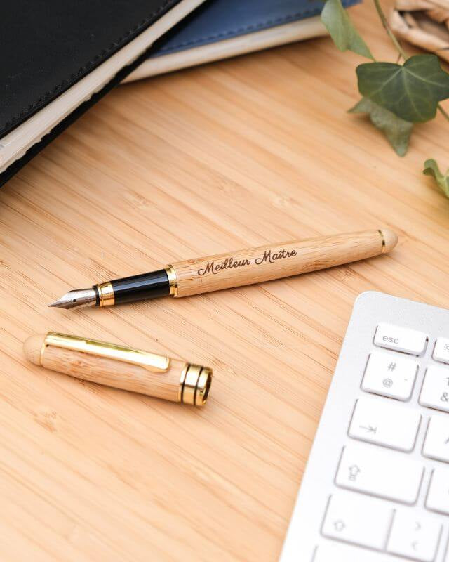 Stylo Plume à Personnaliser - My Bambou posé sur un bureau en bois avec un clavier et un carnet en arrière-plan.