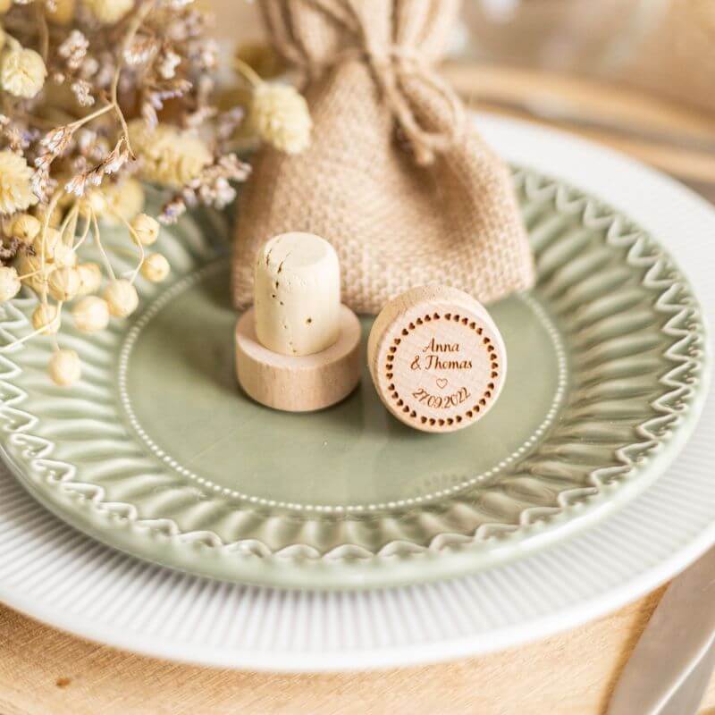 Bouchons de Vin à Personnaliser pour Mariage - My Bambou présentés sur une assiette élégante avec des fleurs séchées.