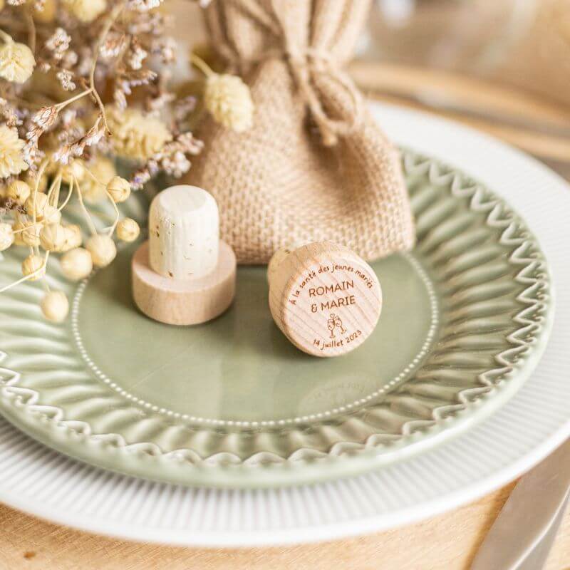 Bouchons de Vin à Personnaliser pour Mariage - My Bambou sur une assiette élégante avec des fleurs séchées.
