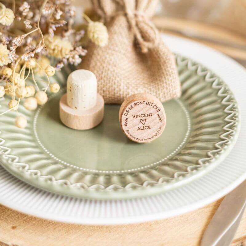 Bouchons de Vin à Personnaliser pour Mariage - My Bambou sur une assiette élégante avec un sachet en toile.